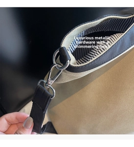 Detail of khaki canvas tote bag showing high-gloss metal hook and striped inner lining