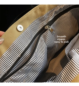 Detail of canvas tote bag showing magnetic buckle, striped lining and smooth inner zipper