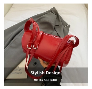 Detail view of red cylindrical bag featuring glossy patent leather and silver metal buckles