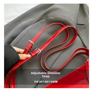 Detail of a red glossy leather shoulder bag featuring an adjustable silver metal buckle strap
