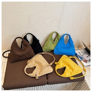 Minimalist triangle suede handbags in six vibrant colors displayed on a soft platform