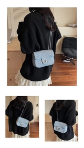 Detail of light blue denim crossbody bag with silver chain strap and quilted stitching