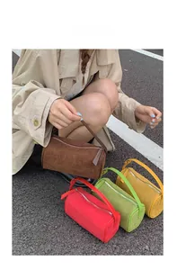 Detail of four colorful suede cylinder pillow bags in brown red green and yellow