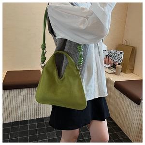 Close-up of matte green crossbody bag with unique knot shoulder strap on model