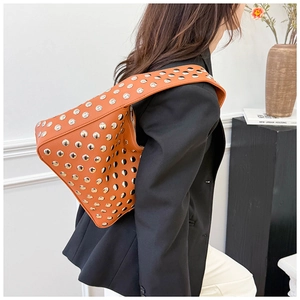 Close-up of orange textured shoulder bag with silver studs and structured curved design
