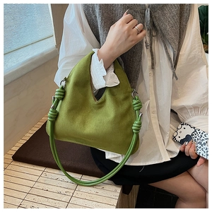 Detail of avocado green suede texture handbag with stylish leather knot and silver ring