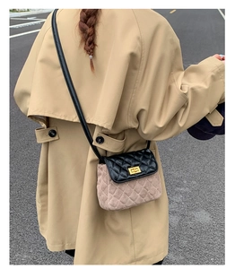 Detail of quilted flap bag in black and beige suede on model wearing a trench coat