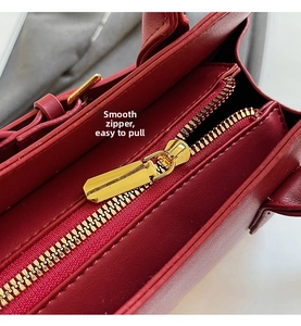 Detail of smooth golden metal zipper closure on luxury red leather wedding handbag