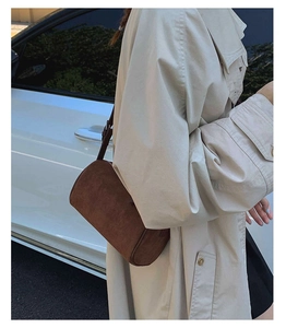 Detail of a dark brown frosted cylinder crossbody bag with minimalist shoulder strap design