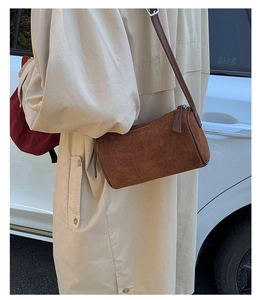 Detailed side view of vintage brown matte cylinder shoulder bag on model in outdoor light