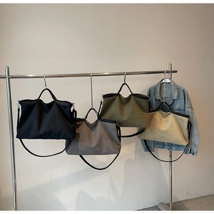 Showcasing four colors of large canvas tote bags on a display rack with shoulder straps