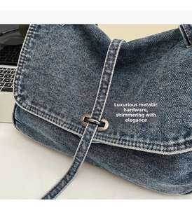 Gros plan détaillé du sac en denim bleu avec boucle en métal vintage et surpiqûres blanches