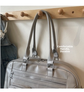 Dettaglio della borsa in ecopelle grigio chiaro con doppi manici e tasche con cerniera