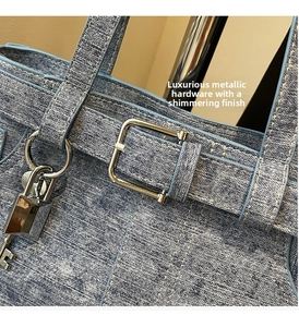 Detail of light blue denim handbag with silver hardware and yellow contrast stitching