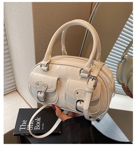 Detail of cream white leather handbag featuring dual flap pockets and silver metal buckles