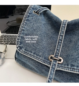 Détail d'un sac à bandoulière en denim bleu foncé avec fermoir rotatif en métal argenté