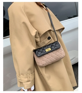 Detailed view of a quilted color-block crossbody bag styled with a khaki trench coat
