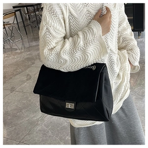 Close-up of black quilted tote bag featuring silver twist lock and chain strap detail