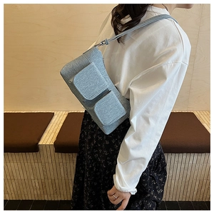 Detail of light blue textured fabric shoulder bag worn by model in minimalist setting