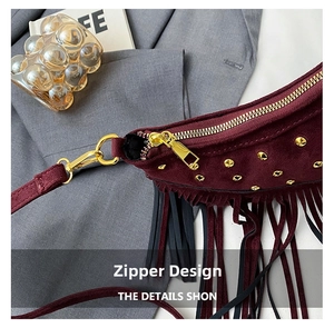 Close-up of vintage burgundy suede crossbody bag with gold rivets and tassel zipper detail