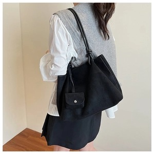 Macro detail of vintage matte black tote bag with strap tassels and small pouch