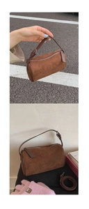 Detail of dark brown suede cylinder bag showing adjustable leather handle and silver zipper