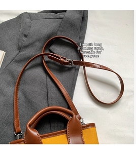Detail of yellow canvas tote bag showing the dark brown leather strap and handle craftsmanship