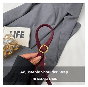 Macro shot of an adjustable burgundy suede shoulder strap with a gold metal buckle