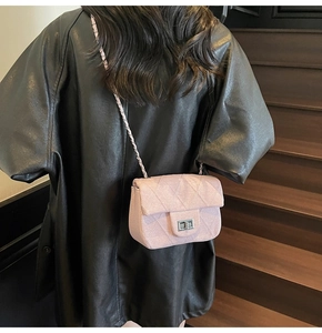 Detail of pink quilted small square bag with silver clasp on a model in a black leather jacket