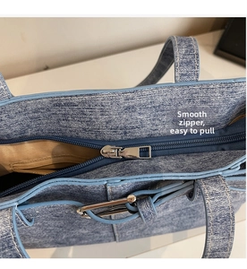 Detail showing smooth blue metal zipper and denim edges of the stylish tote bag