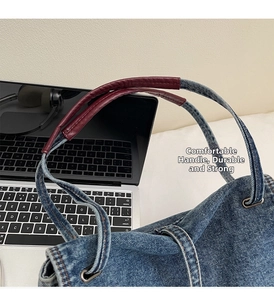 Détail des poignées en cuir rouge et des œillets sur le sac cabas en jean pour bureau