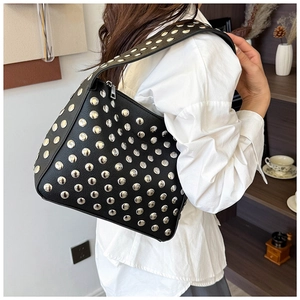Detail of black pebbled leather shoulder bag with silver studs on a female model