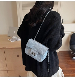 Close-up of light blue sequined crossbody bag with silver chain and metal lock detail