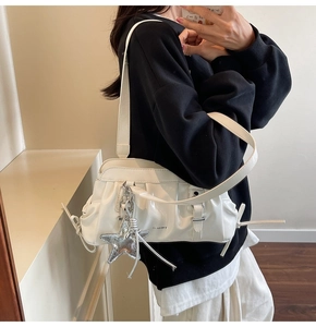Detail of white ruched hobo bag with shiny finish and silver star pendant accessory