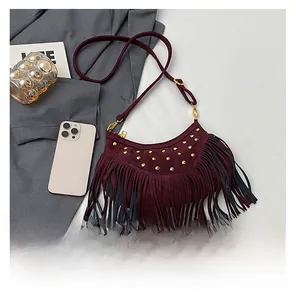 Close-up of wine red suede crossbody bag with vintage rivets and long tassels detail
