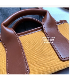 Detail view of mustard yellow canvas fabric and brown leather trim on a retro pillow bag