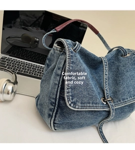 Détail du sac bandoulière en jean bleu avec poignée en cuir et anneaux argentés