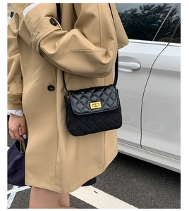 Close-up of black quilted shoulder bag with gold twist lock and mixed leather texture
