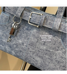 Detail of blue washed denim handbag with silver belt buckles and decorative metal padlock