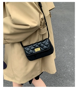 Close-up of quilted cross-body bag featuring a gold square turn-lock and leather strap