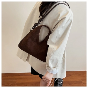 Detail of dark brown matte suede crescent bag with adjustable knotted shoulder strap