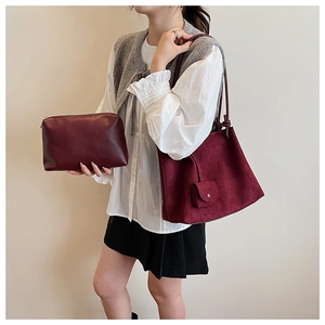 Detail of burgundy matte tote and matching clutch set worn by a model in profile view