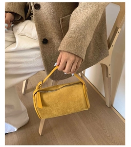 Detail view of bright yellow frosted underarm bag with metal zipper and long leather puller