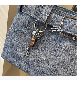 Detail of blue denim handbag featuring silver metal padlock and white contrast stitching