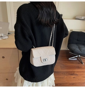 Detail of cream quilted chain shoulder bag shown on model in a stylish office setting