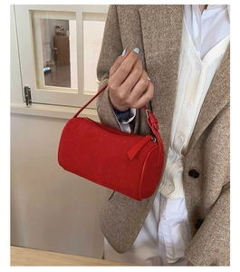 Close-up of a red suede cylinder handbag paired with a stylish brown tweed blazer