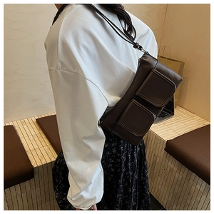 Close-up of minimalist dark brown shoulder bag featuring functional utility pockets