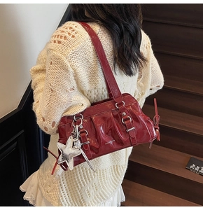 Detail of red patent leather shoulder bag with glossy finish and star pendant