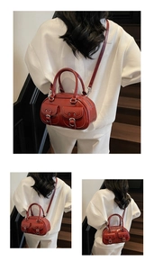 Red patent leather handbag with retro silver buckles and dual pockets on dark stairs