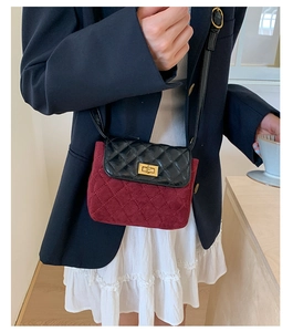Detail of burgundy and black quilted crossbody bag with golden twist lock on model